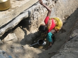 <p>This young lady is collecting water to drink from a tiny pipe in a ditch on the side of the road. Clean water is hard to find in India.</p>